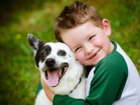 Child lovingly embraces his pet dog, a blue heeler